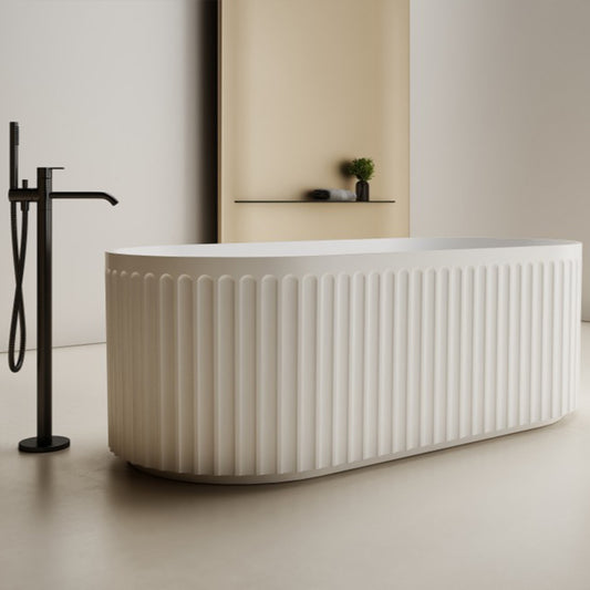 Modern white freestanding bathtub with black faucet in a minimalistic bathroom.